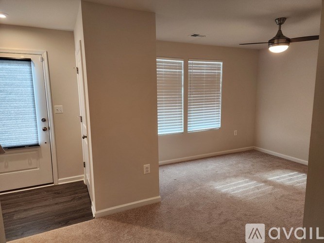 A room with a door, a window with blinds, and a ceiling fan.