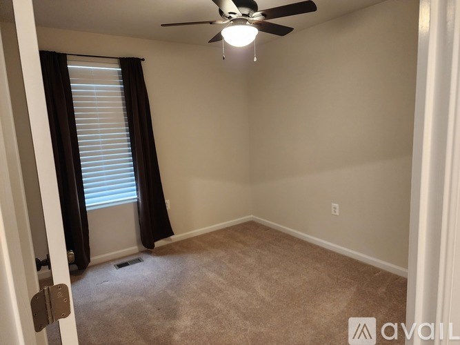 A room with a ceiling fan and carpeted floor.