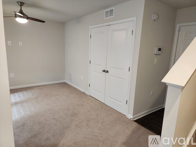 A room with a white door and a ceiling fan.