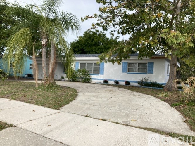A blue house with a white fence and a tree in front.