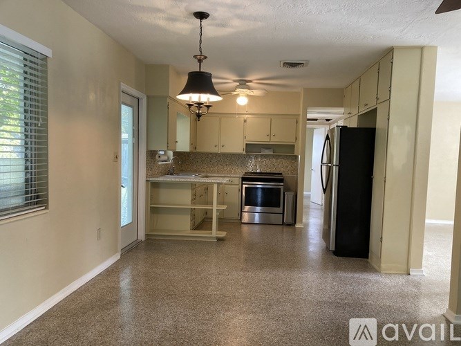 A kitchen with a black fridge and a ceiling fan.