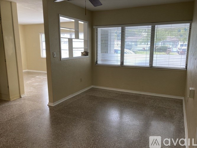 A room with a carpeted floor and a window with blinds.