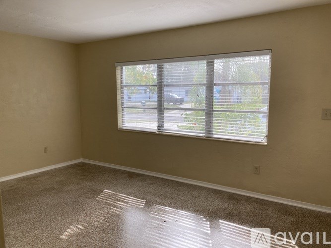 A room with a large window covered in blinds.