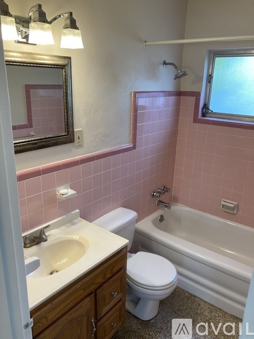A bathroom with pink tiles and a white toilet.