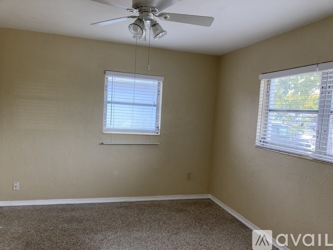 A room with a ceiling fan and two windows.