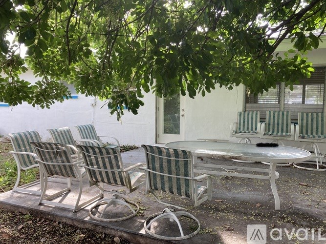 A white table and chairs are set up under a tree.