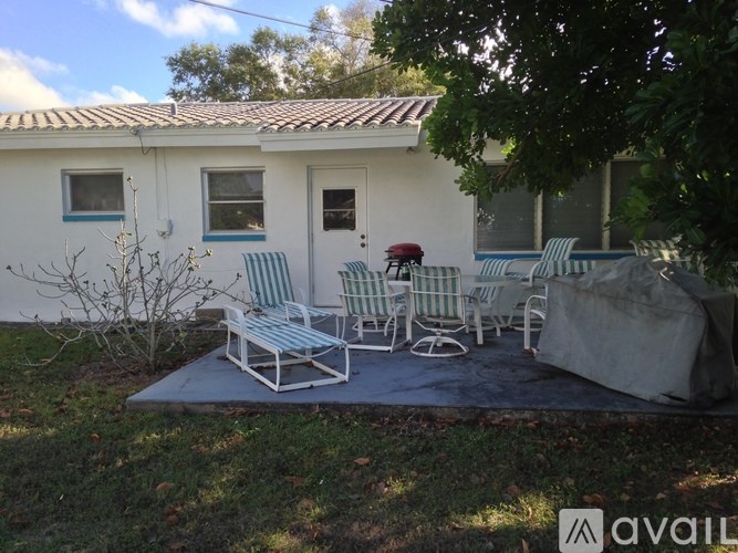 A white house with a blue door and a patio with chairs.