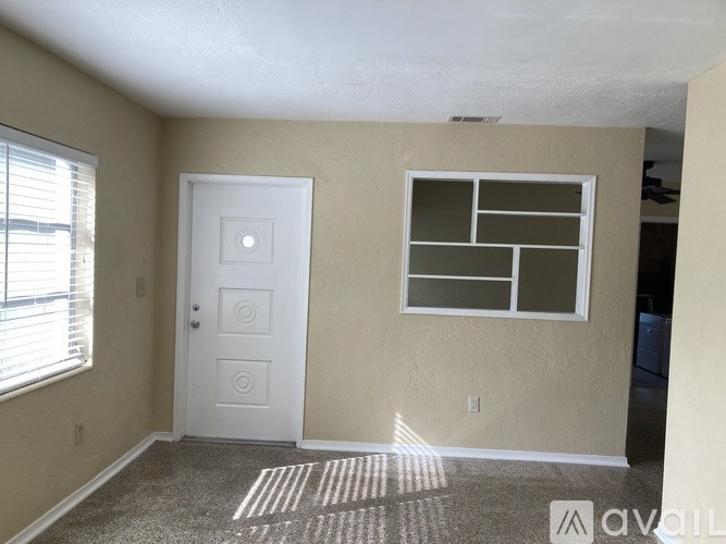 A room with a white door and a window with blinds.