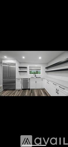 A modern kitchen with white cabinets and a wooden floor.