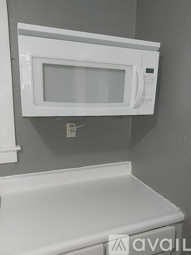 A white microwave oven mounted above a white countertop.