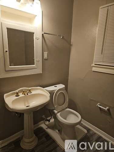 A bathroom with a toilet, sink, and mirror.