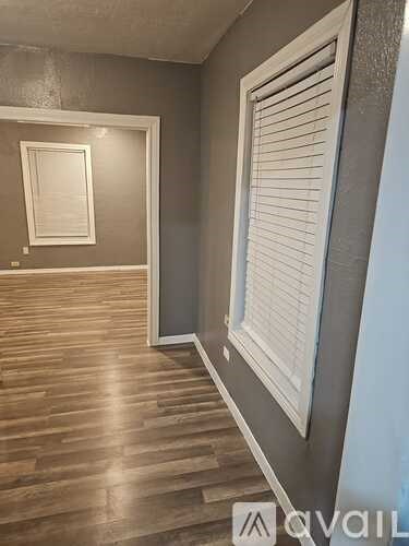A room with a wooden floor and a window with white blinds.
