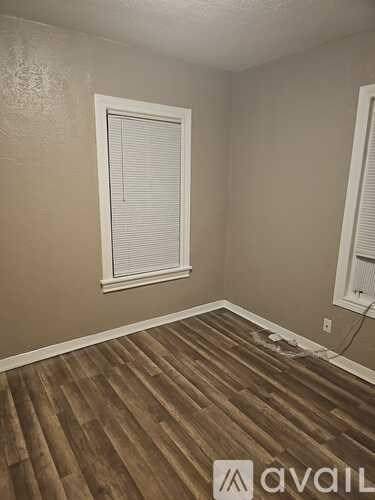 A room with wooden flooring and a window with blinds.