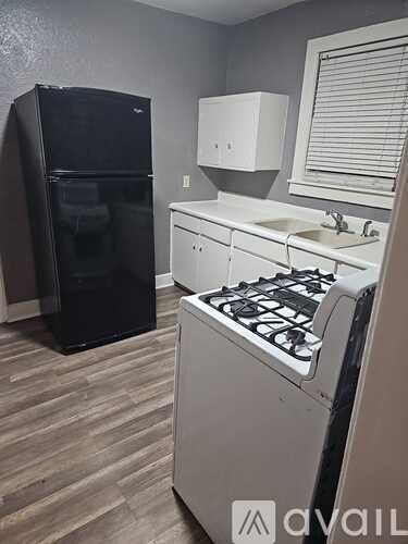 A kitchen with a black fridge, white cabinets, and a white stove.