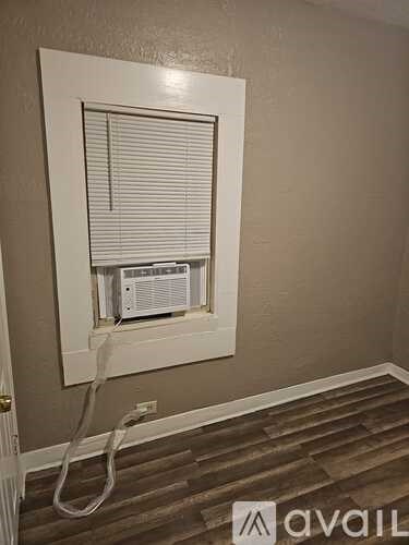 A wall-mounted air conditioner unit with a white frame and a white hose attached to it.