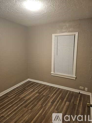 A room with wooden flooring and a window with blinds.