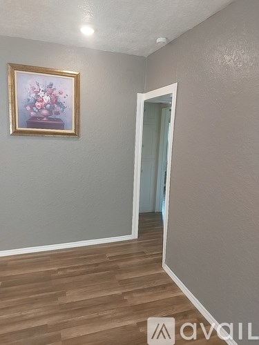 A room with a painting on the wall and wooden flooring.