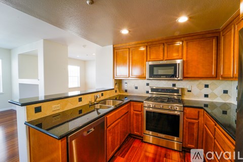 A kitchen with wooden cabinets and a black counter top.
