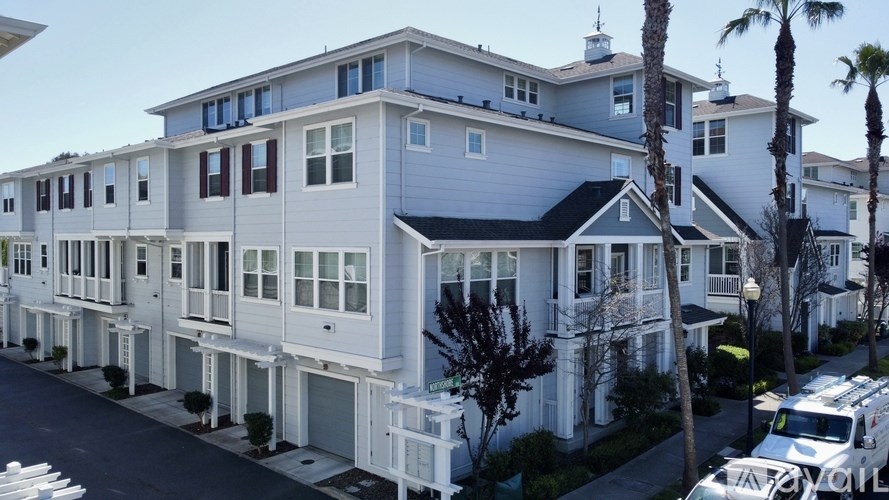 A row of white houses with a truck parked in front of them.