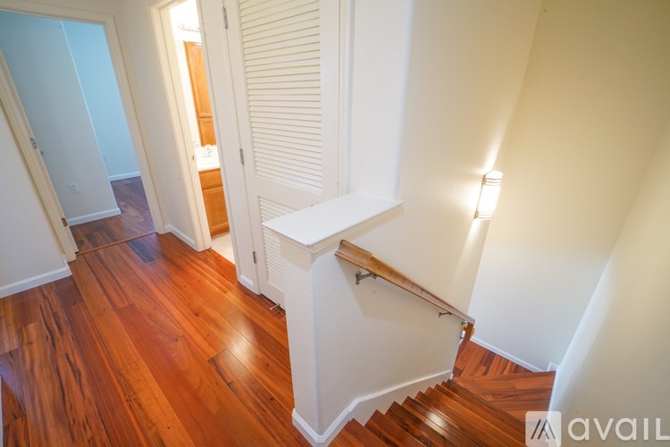 A hallway with a staircase and wooden floors.