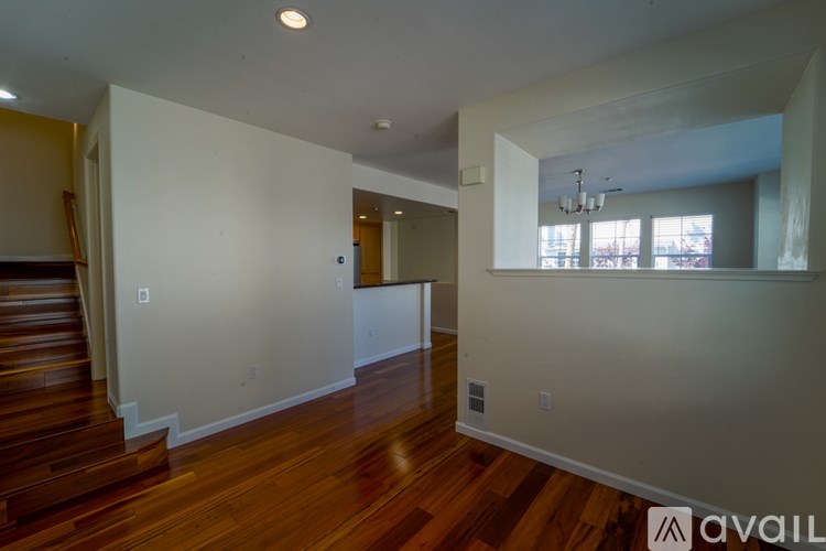 A spacious room with wooden floors and white walls.