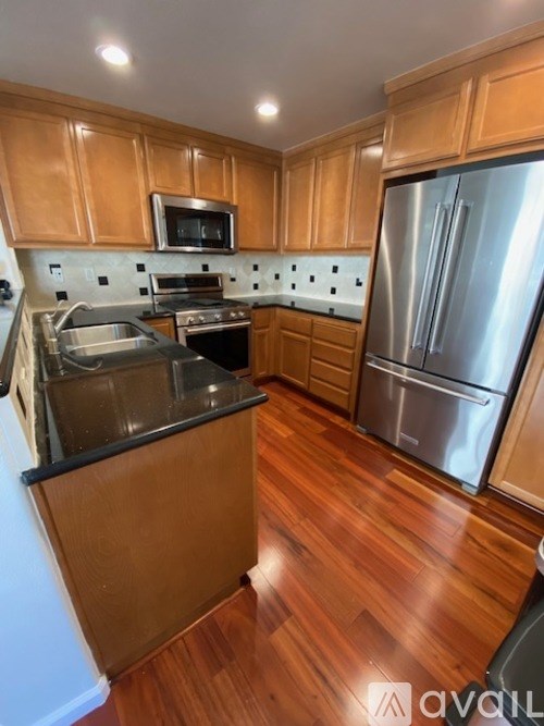 A kitchen with wooden cabinets and a stainless steel refrigerator.