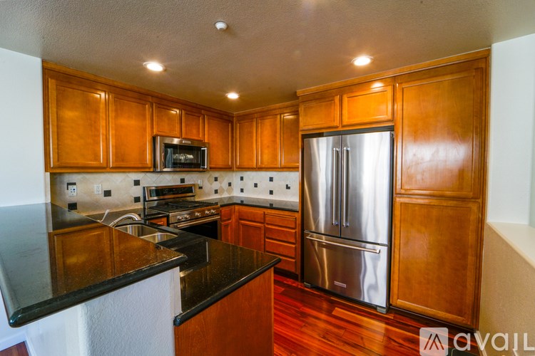 A kitchen with wooden cabinets and a stainless steel refrigerator.