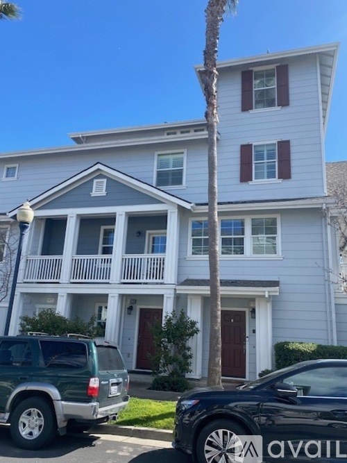 A two-story house with a balcony and a palm tree in front.