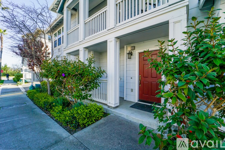 A white house with a red door and a small garden in front.