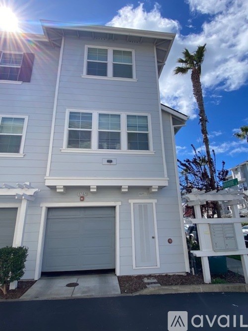 A two-story house with a garage door and a palm tree in front.