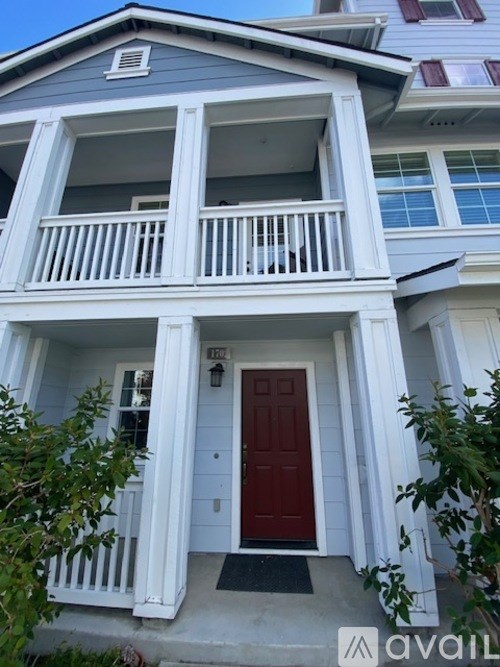 A two-story house with a red door and white railings.