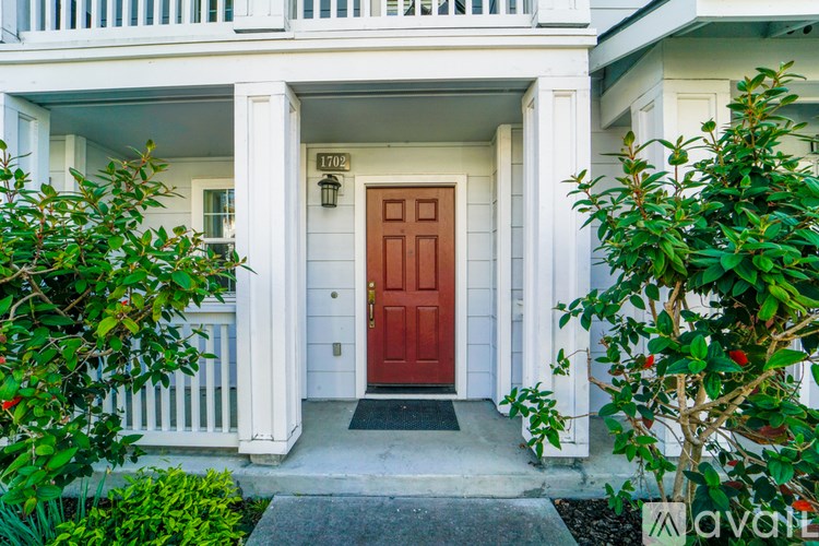 A white house with a red door and a white porch.