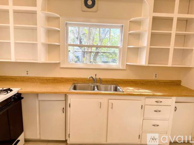 A kitchen with white cabinets and a wooden countertop.