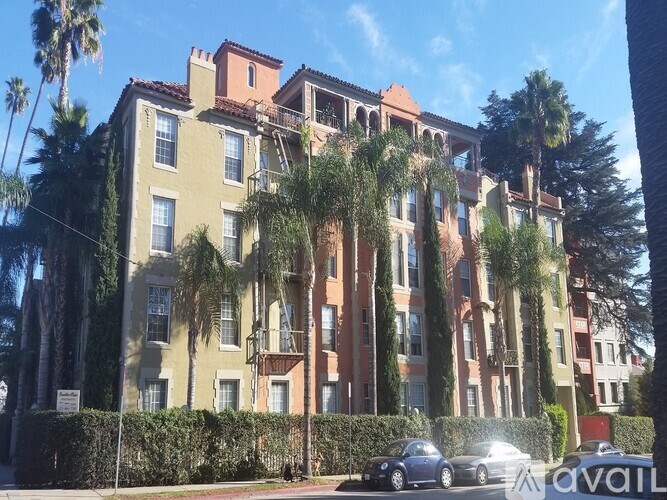 A row of multi-story apartment buildings with balconies and trees in front.