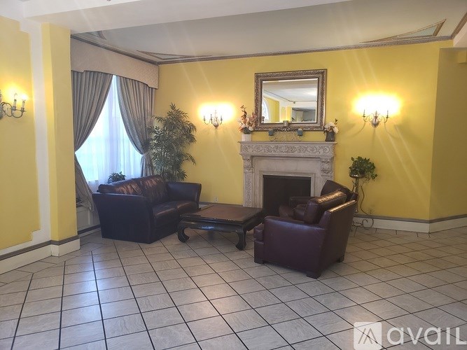 A living room with a fireplace, two chairs and a sofa.