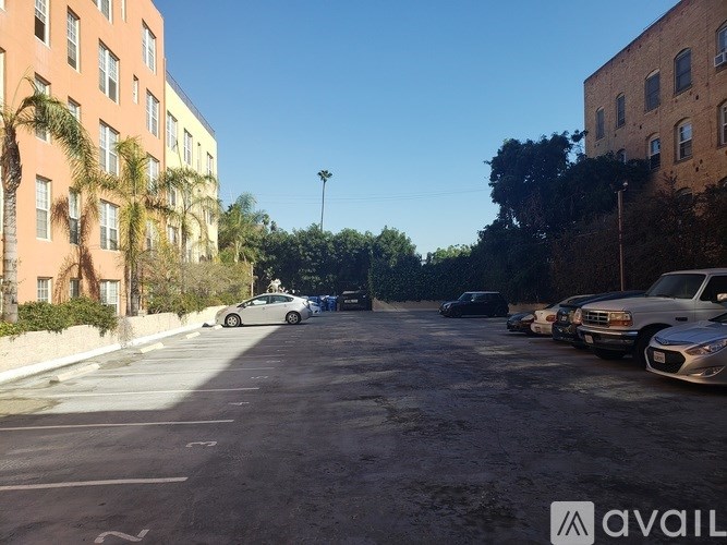 A parking lot with cars and buildings on either side.