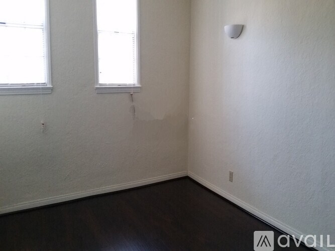 A room with a window and a smoke detector on the wall.