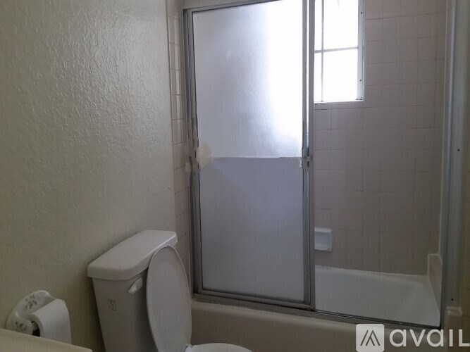 A bathroom with a toilet, a glass shower door, and a window.