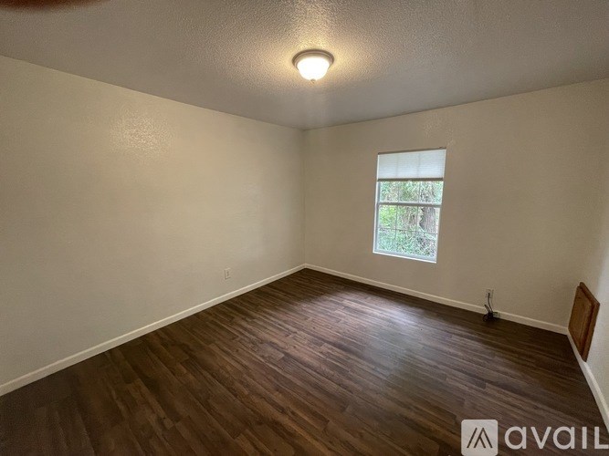 A room with wooden flooring and a window letting in natural light.