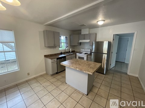 A kitchen with a white tile floor and a countertop with a sink.