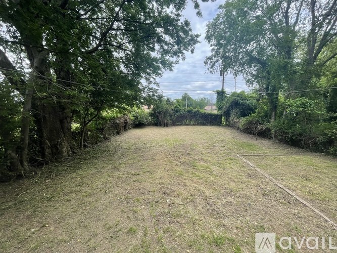 A grassy field with trees on the sides and a fence in the distance.