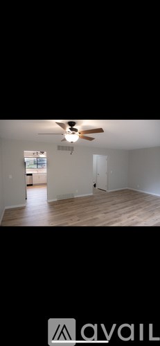 A room with a ceiling fan and wooden flooring.