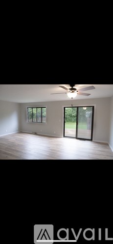 A room with a ceiling fan and sliding glass doors.