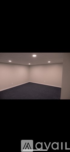 A room with a carpeted floor and a wall with a single light fixture.