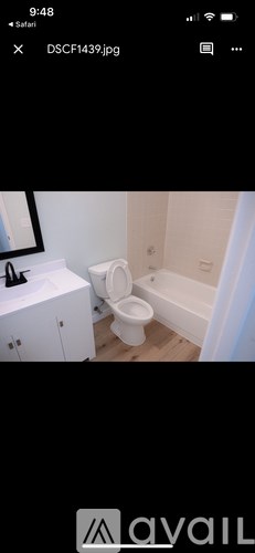 A white toilet is in a bathroom with a white cabinet and a mirror.