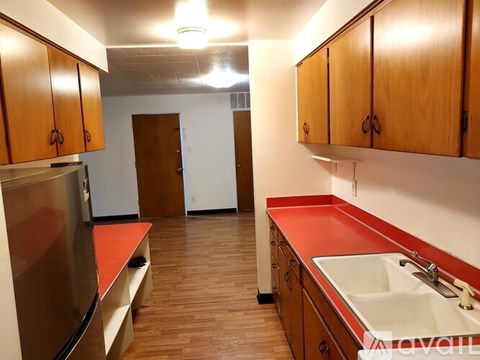 A kitchen with wooden cabinets and a red counter.