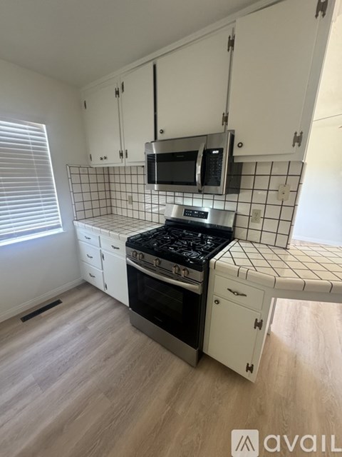 A kitchen with white cabinets and a black stove top oven.