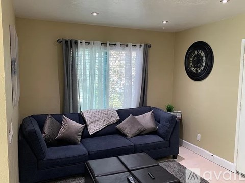 A living room with a blue couch and a clock on the wall.