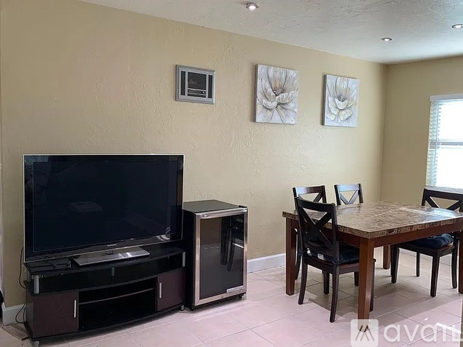 A living room with a television, a table, and chairs.