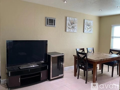 A living room with a television, a table, and chairs.